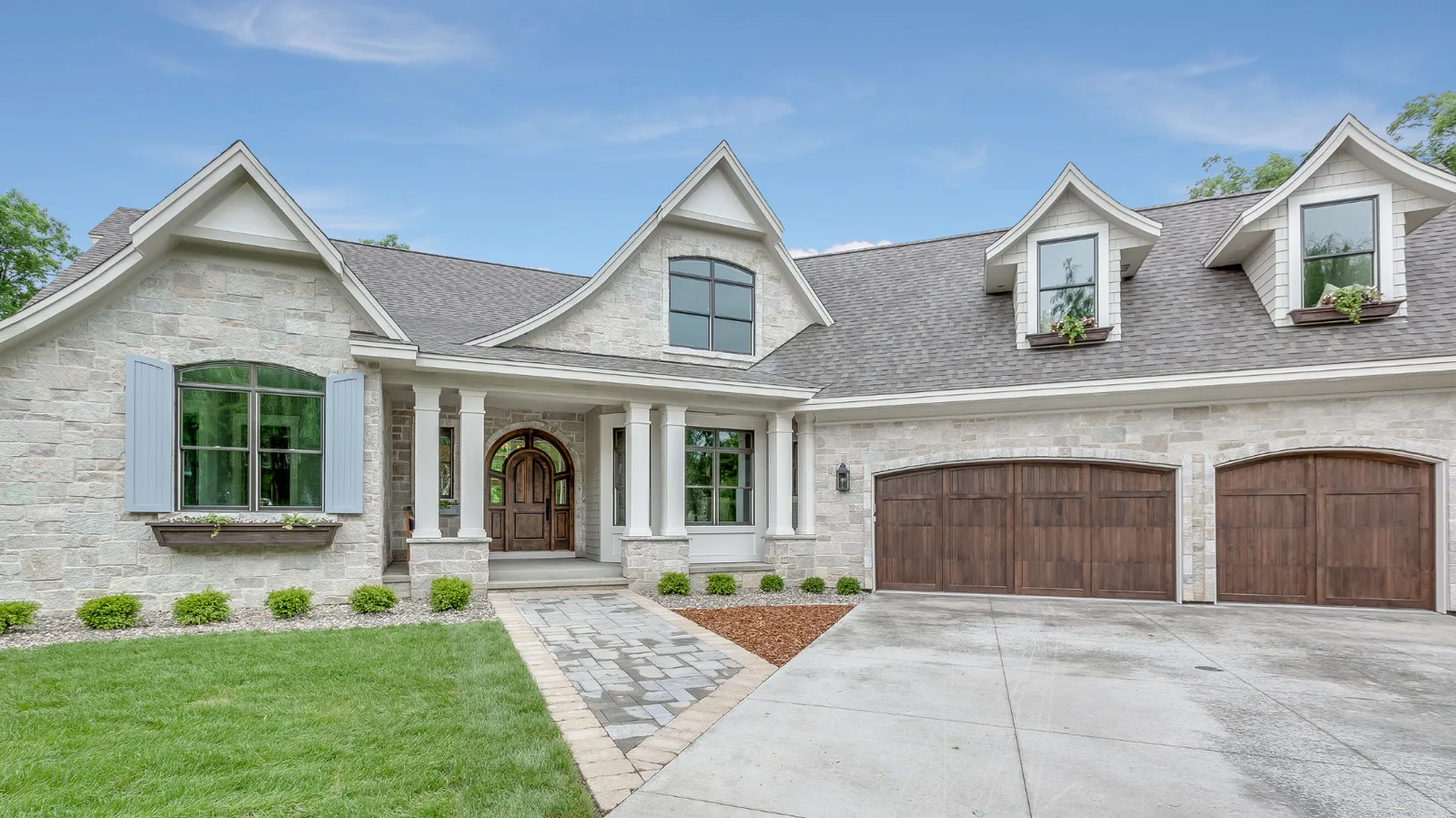 Light stone house with a gray shingle roof and blue-gray shutters