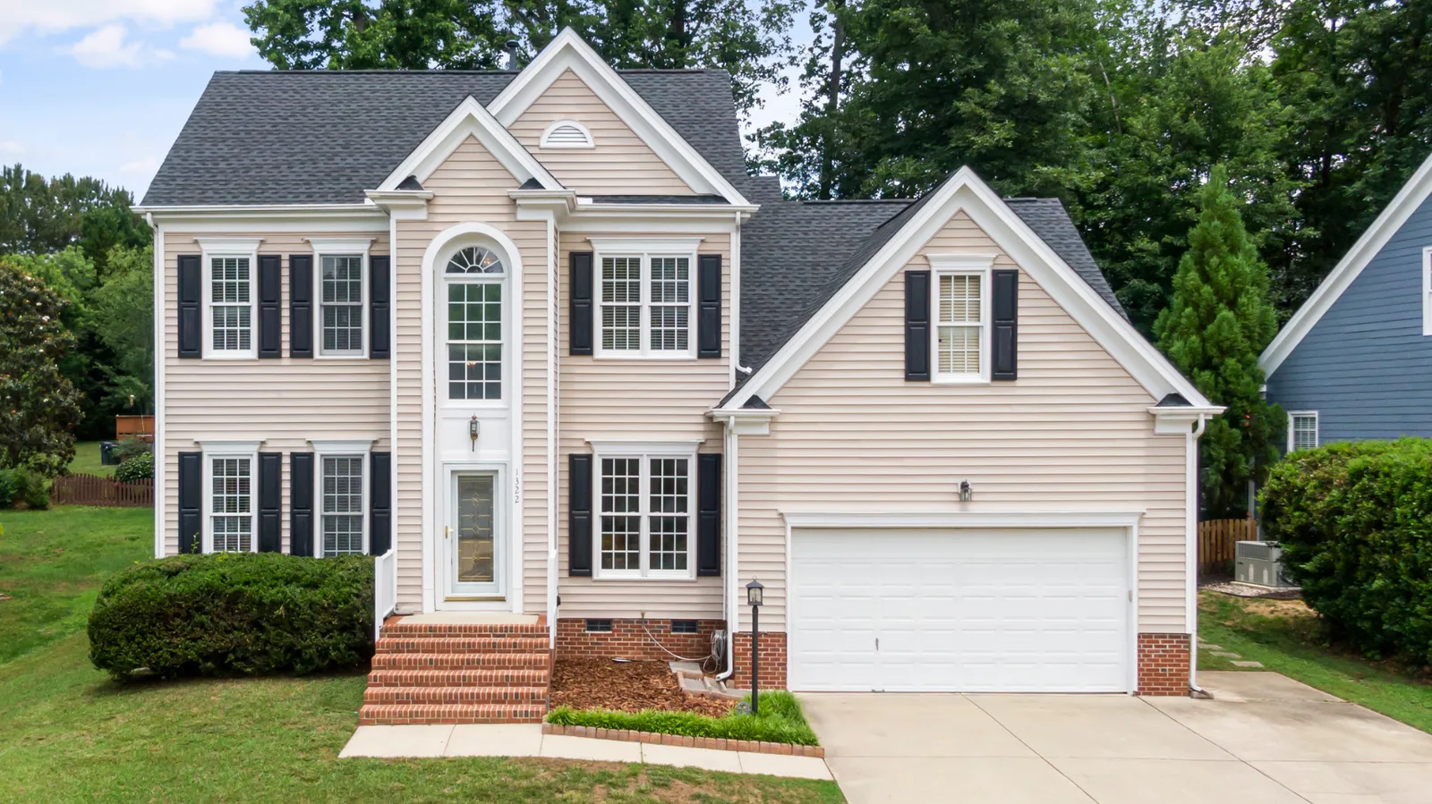 Two-story house with a dark shingle roof and black shutters